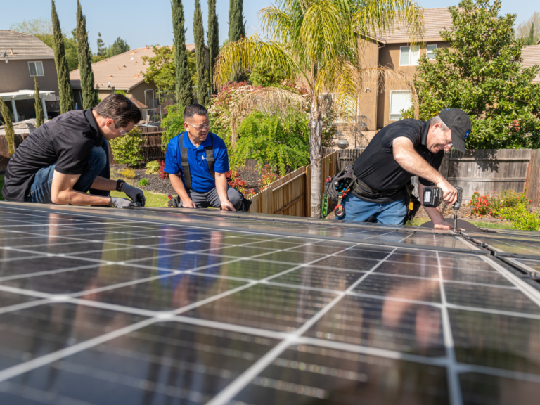 3 men installing solar panels on a roof